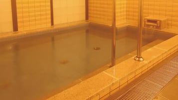 A swimming pool with a metal ladder, tiled walls, and a drain.