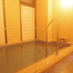 A swimming pool with a metal ladder, tiled walls, and a drain.