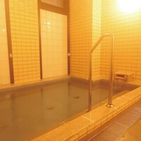 Una piscina con escalera metálica, paredes con azulejos y un desagüe.