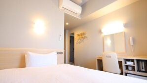 A hotel room with a bed, a desk, a chair, a mirror, and an air conditioning unit. - Ab Hotel Kamagori (Gamagori)