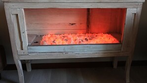 Un mueble de madera rústica con un estante que contiene un objeto rojo brillante.