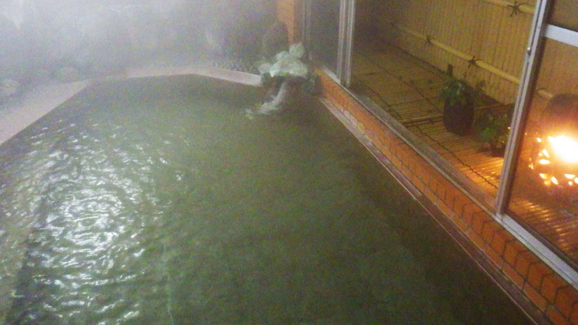 Een bubbelbad met uitzicht op een bakstenen muur en een raam.