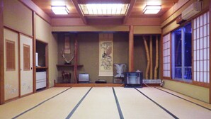 A tatami mat room with a traditional Japanese shoji screen, a desk with a computer, and a decorative wall hanging. - Deyu Onsen Oishiya Ryokan (Agano)