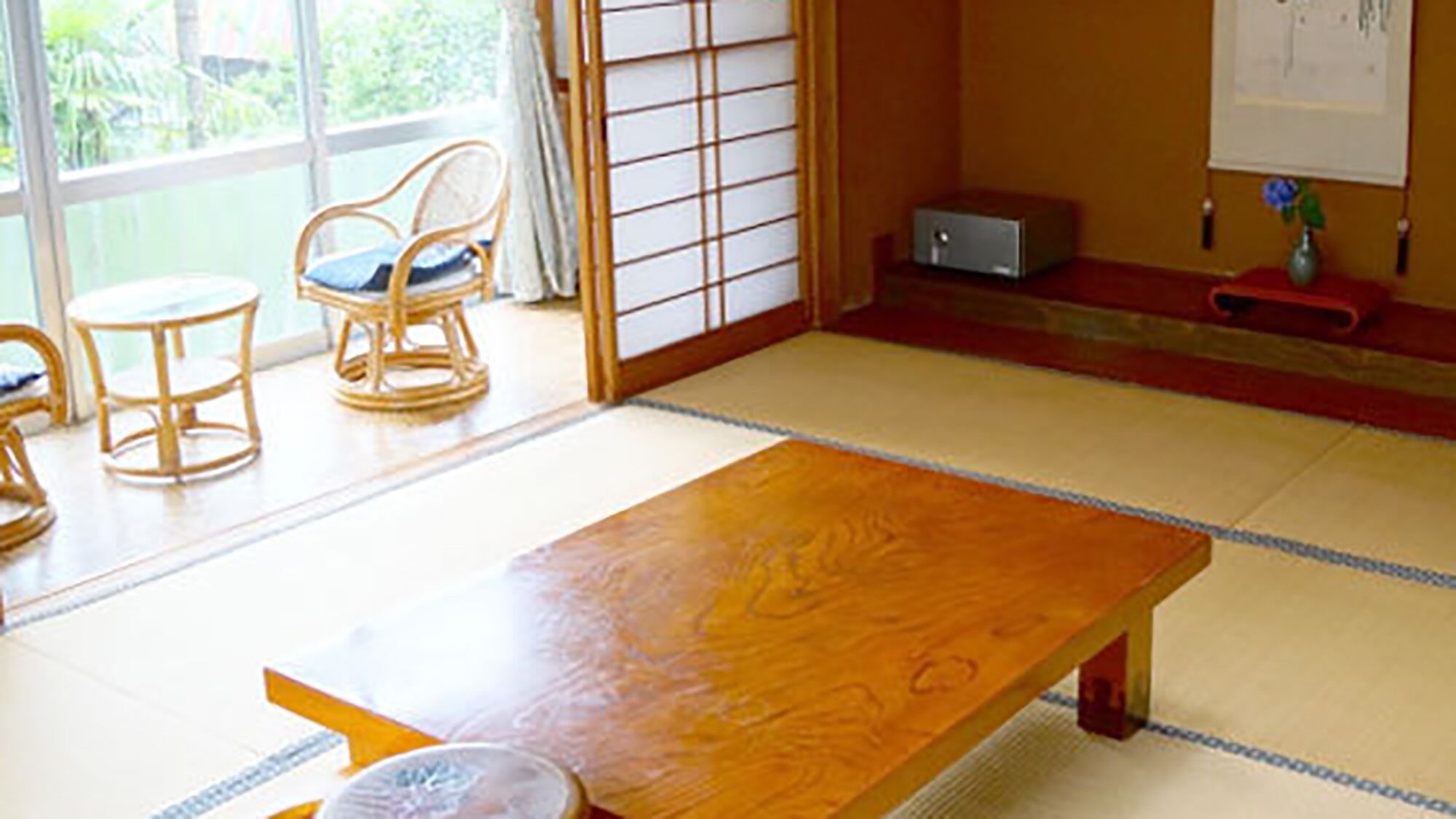 A traditional Japanese room with tatami flooring, a low wooden table, and two tatami mats chairs.