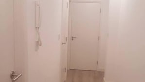 Un estrecho pasillo con suelo de madera y paredes blancas.