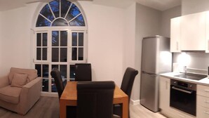 Una cocina compacta con comedor, un ventanal grande y un refrigerador moderno.