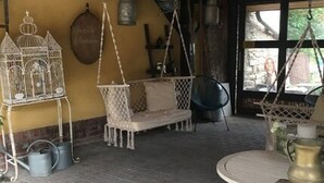 Ein rustikales Interieur mit einem Hängestuhl, einem kleinen Tisch und einem Vogelkäfig.