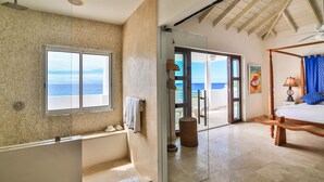 A bedroom with a large window, a four-poster bed, and a view of the sea. - Dream Villa Shore Point 552 (Lowlands)
