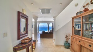 A hallway with a view to the sea, a wooden cabinet with glass doors, and a mirror on the left. - Dream Villa Shore Point 552 (Lowlands)