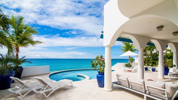 A poolside area with lounge chairs and a view of the ocean. - Dream Villa Shore Point 552 (Lowlands)