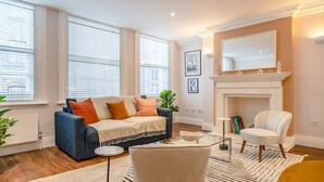 Ein Wohnzimmer mit einer Couch, Sesseln, einem Kamin und einem großen Fenster.