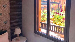 A room with a window overlooking a garden with colorful flowers and a wooden deck. - Splendid Apartment in the Jardins de l'Atlas 4620 (Marrakech)