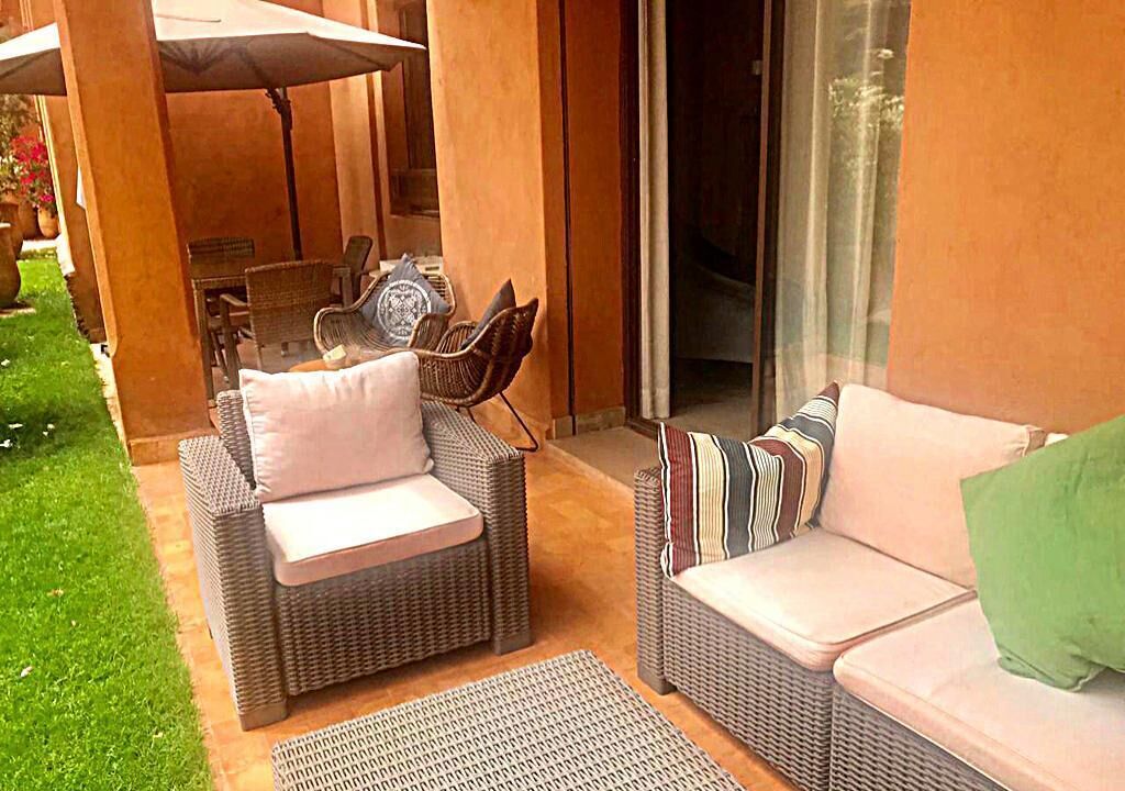 An outdoor seating area with wicker furniture and a covered table.