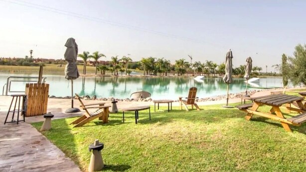 A poolside area with lounge chairs, a small table, and a statue. - Splendid Apartment in the Jardins de l'Atlas 4620 (Marrakech)