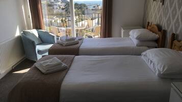 A hotel room with two beds, a view of the city, and a balcony.