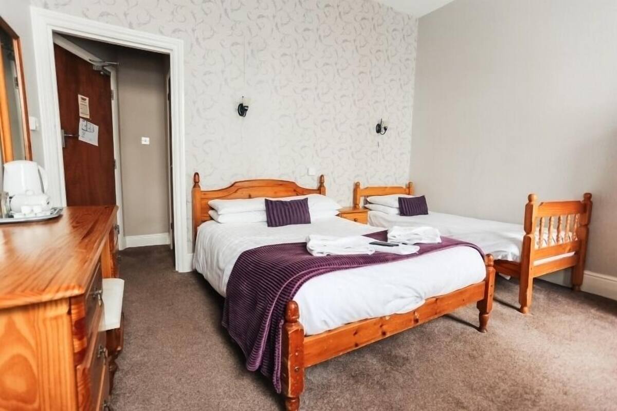 Quarto com duas camas de solteiro, um aparador de madeira e uma cadeira.