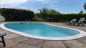 A rectangular swimming pool with a tiled edge, surrounded by a brick patio. - Nethway Hotel (Torquay)