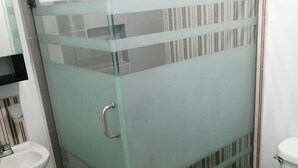 Casa de banho com chuveiro em cabine de vidro, lavatório e sanita.
