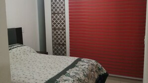 Quarto com cama, porta deslizante vermelha, painel decorativo e luminária de teto.