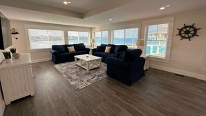 A spacious living room with two dark blue sofas, a white coffee table, and a large window with blinds. - The Pioneer - York Beachfront living (York)