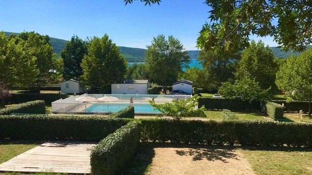 A pool area with a wooden deck, surrounded by neatly trimmed hedges and trees. - Les Bastides de Chanteraine (Aiguines)