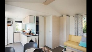 A compact living space with a kitchenette, a dining area, and a seating area with a sofa. - Les Bastides de Chanteraine (Aiguines)