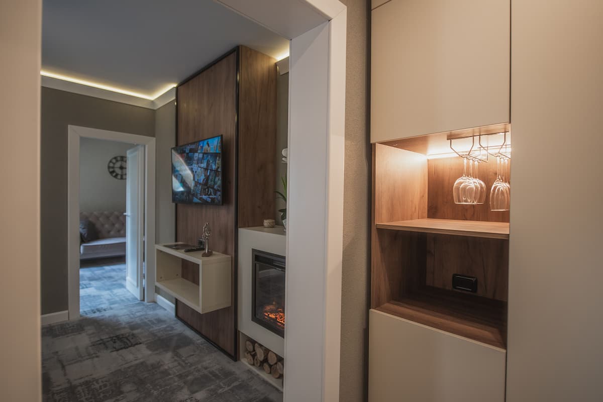 A modern interior with a fireplace, wooden shelving, and a television.
