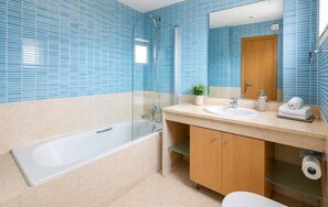 A bathroom with a bathtub, a sink, a mirror, and a toilet. - Villa Lidia Oura Beach with private Swimmingpool (Albufeira)