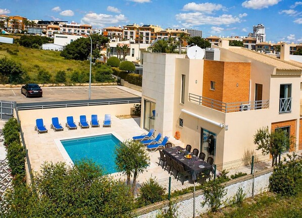 A modern building with a swimming pool, lounge chairs, and a dining area. - Villa Lidia Oura Beach with private Swimmingpool (Albufeira)