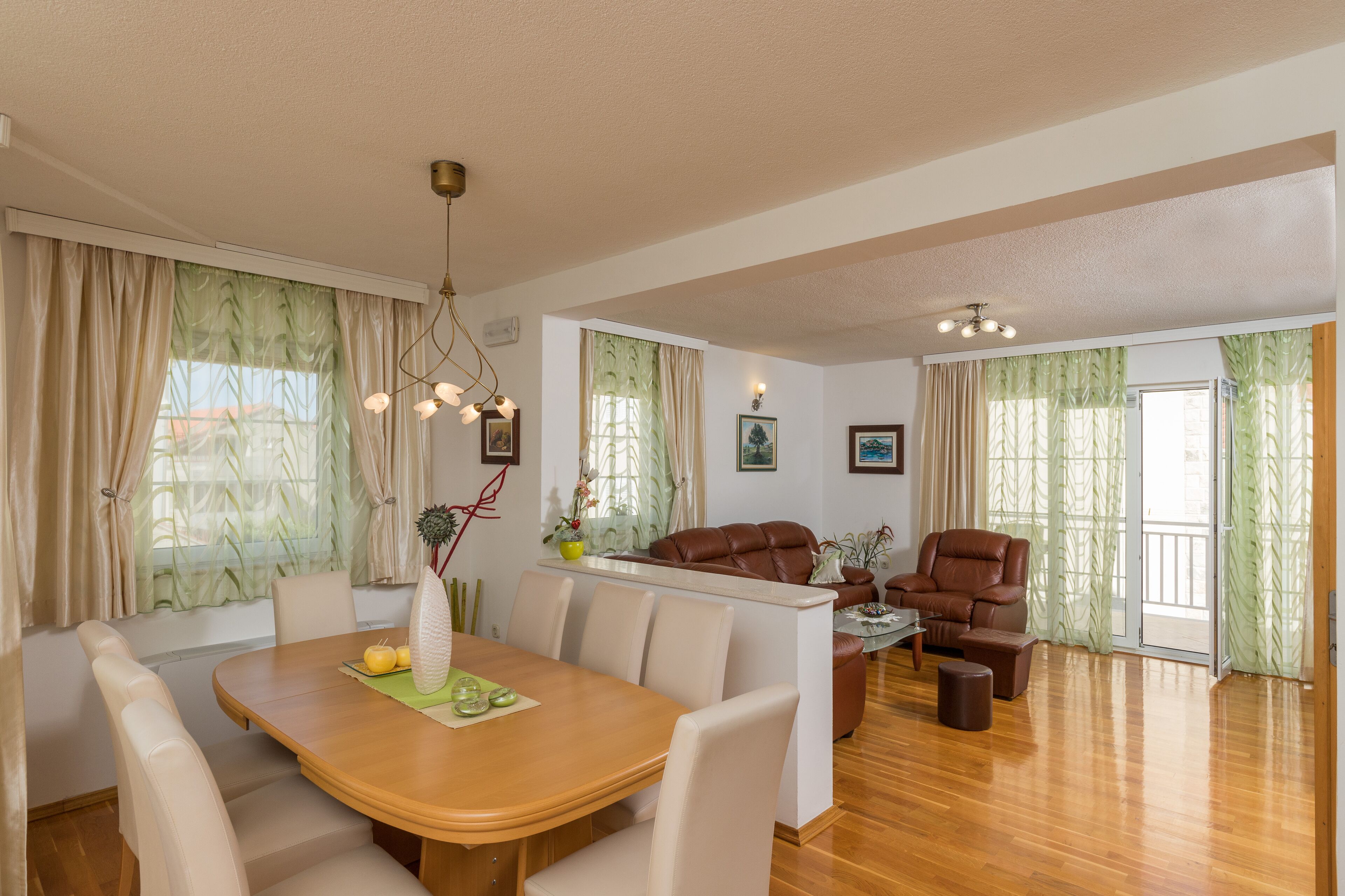 Amplia sala de estar con comedor, que cuenta con una mesa de comedor de madera, asientos cómodos y ventanas grandes con cortinas.