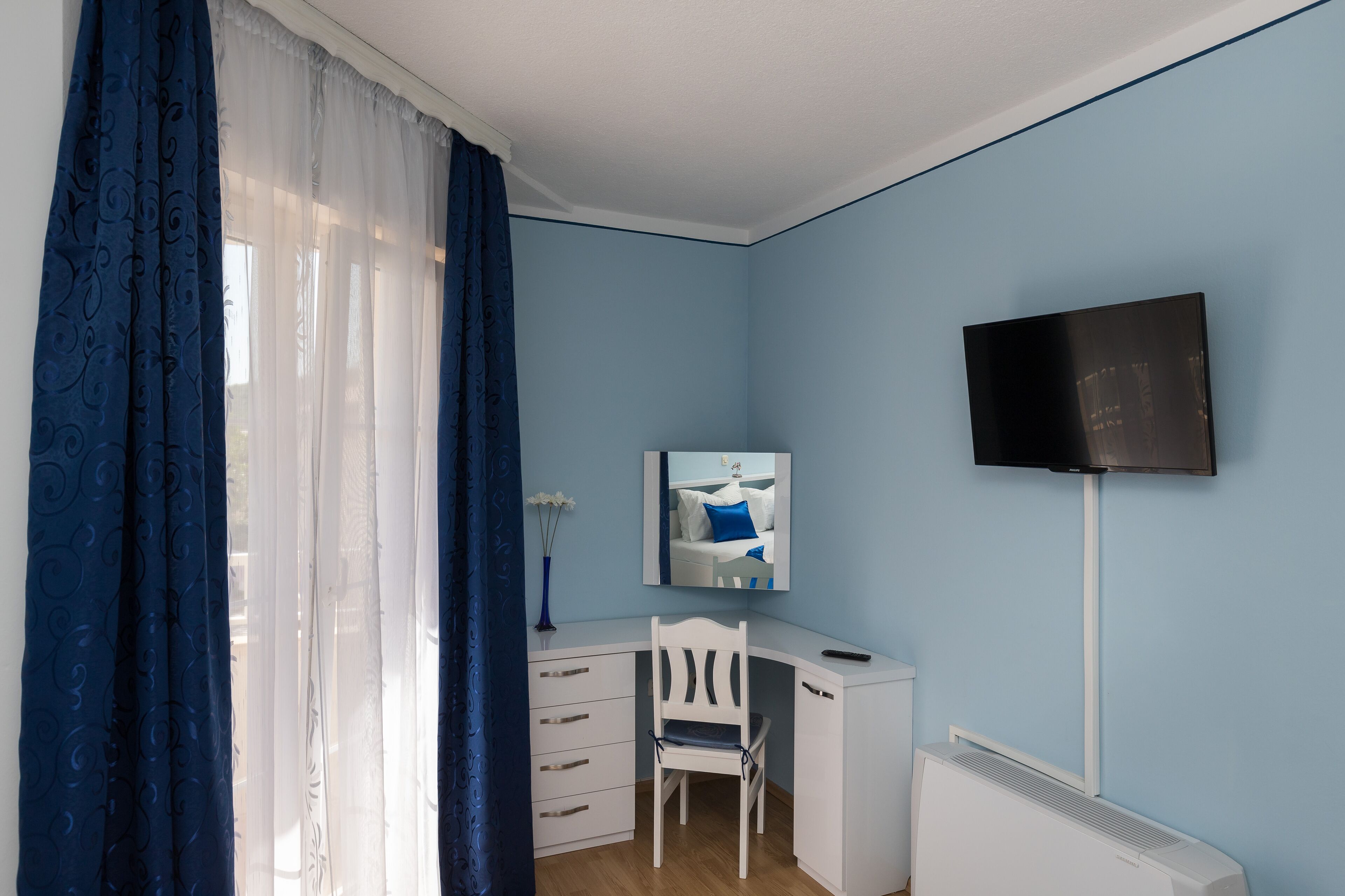 Un dormitorio con escritorio, silla y televisor montado en la pared.