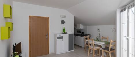 Un espacio habitable compacto con kitchenette, comedor y una pequeña zona de estar.