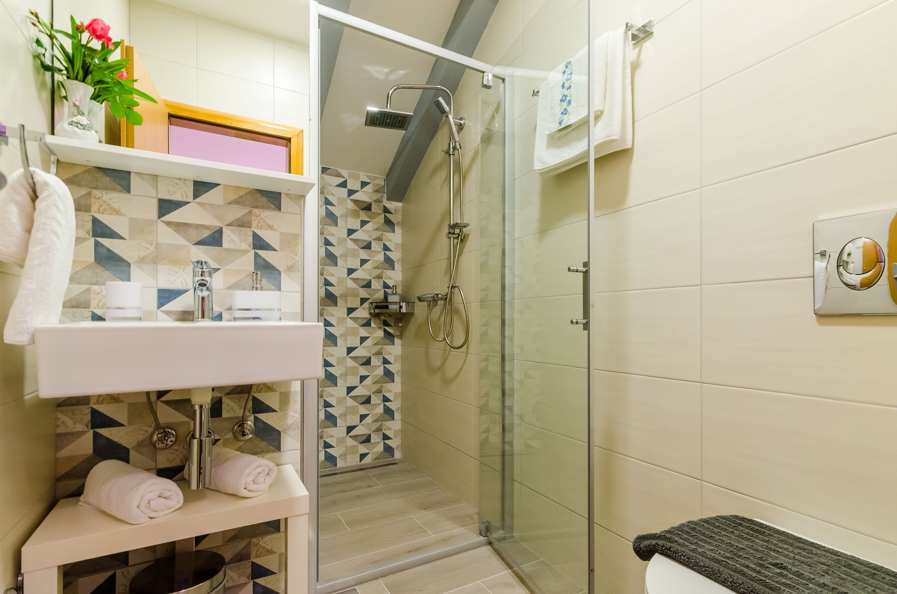 A bathroom with a shower, sink, and towel rack.