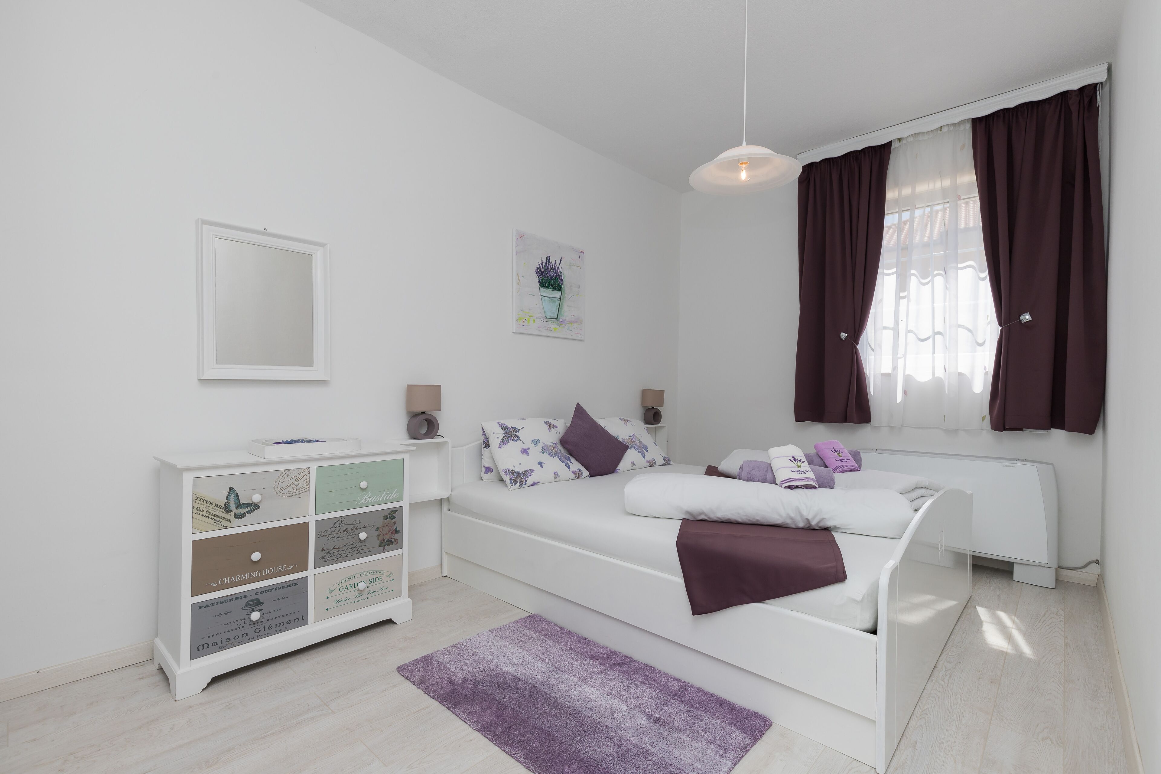 Quarto moderno com cama, penteoude e arte na parede.