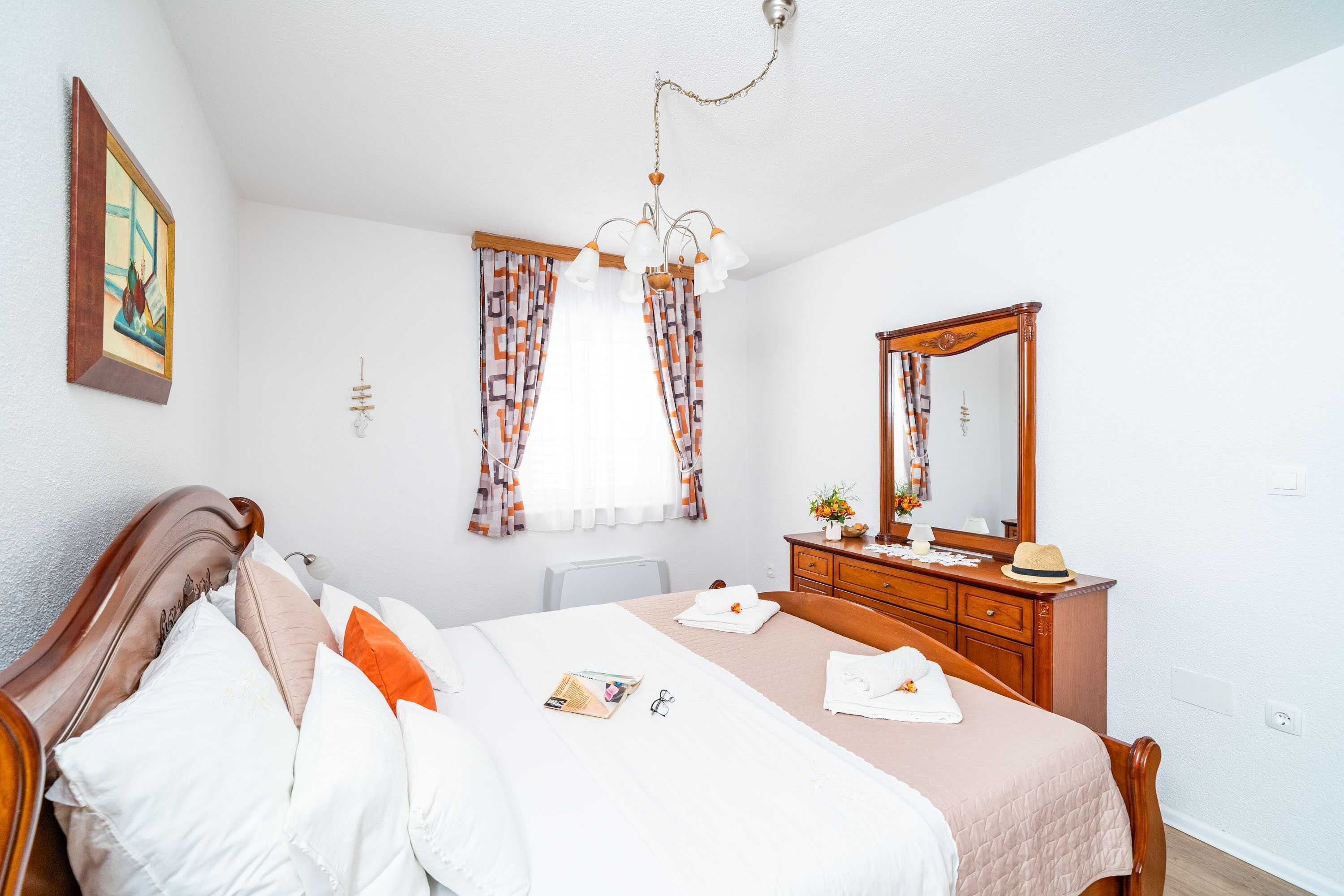 Een keurig opgemaakt slaapkamer met een bed, nachtkastje, kaptafel en een spiegel.