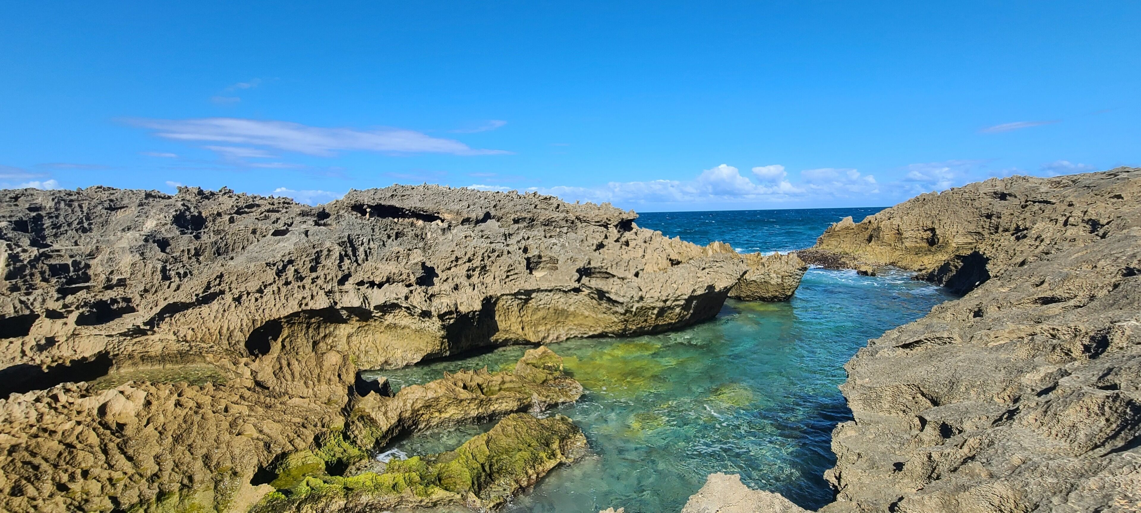 A rocky coastal landscape with clear water flowing through a natural rock formation.