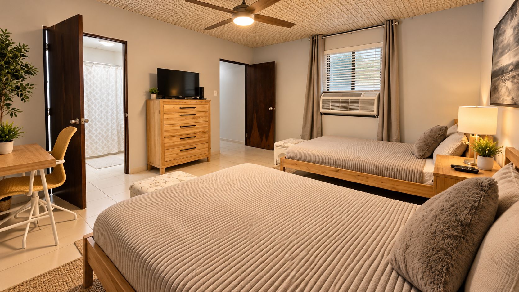 Ein Schlafzimmer mit zwei Betten, einem Schreibtisch, einer Kommode und einem Deckenventilator.