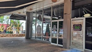 A storefront with large glass windows, a sign for 'JAMON' and 'SCUZI ITALIAN CUISINE', and a Christmas tree visible through the window. -  HEART OF SAN JUAN (Santurce)
