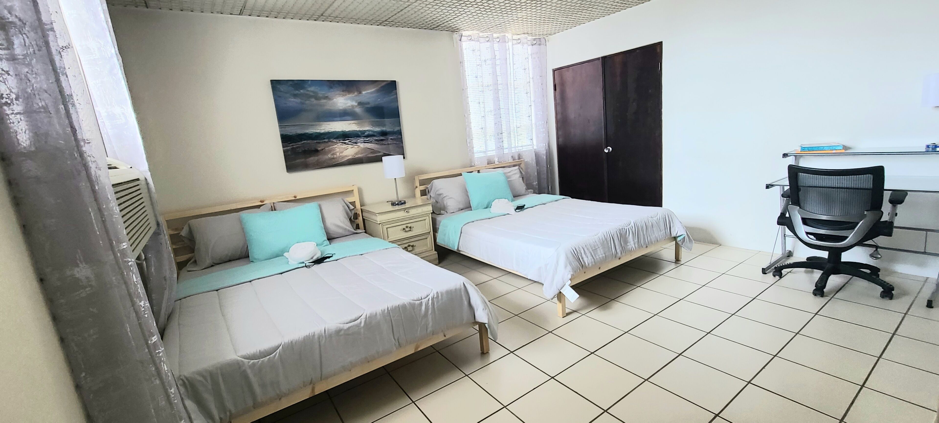 A bedroom with two beds, a desk, and a chair.