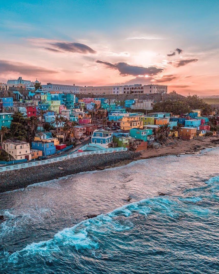 A coastal town with colorful buildings, a beach, and waves crashing onto the shore.