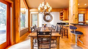 A spacious dining area with a wooden table, chairs, and a chandelier.