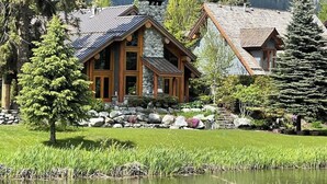 A lodge with a stone facade, wooden beams, and a pond in front.