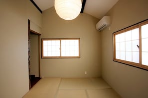 Une pièce dotée d’un sol recouvert de tatamis, d’un paravent shoji, d’une porte coulissante et d’un ventilateur de plafond.