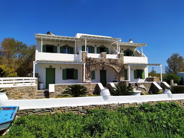 A two-story white building with green shutters, stone accents, and a stone archway.