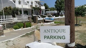 Señal que dice 'ANTIQUE PARKING' frente a un edificio con un muro de piedra y un bote.