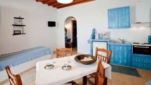 Un comedor con una mesa dispuesta para dos personas, un armario azul con estufa y techo de madera.