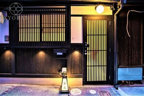 A traditional Japanese building with a wooden exterior, a sliding gate, and a small shrine-like structure in front.