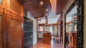 A hallway with wooden flooring, a kitchen area with a stove, and a large mirror with an ornate frame.