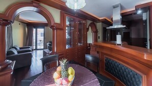 A dining area with a round table, a fruit bowl, and a chandelier.