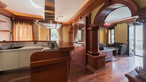 A spacious living area with a kitchen, wooden flooring, and a balcony with a view.